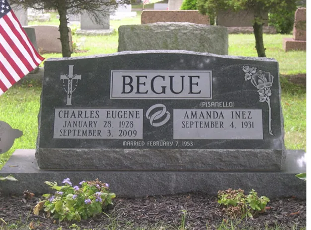 A traditional upright granite monument with an American flag