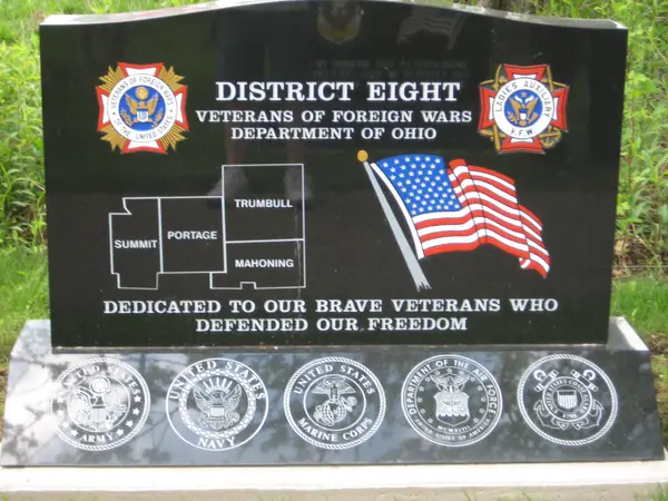 A polished black granite veterans memorial for VFW Department of Ohio District Eight, etched with a map of Summit, Portage, Trumbull and Mahoning counties and an American flag, with five service seals along the base