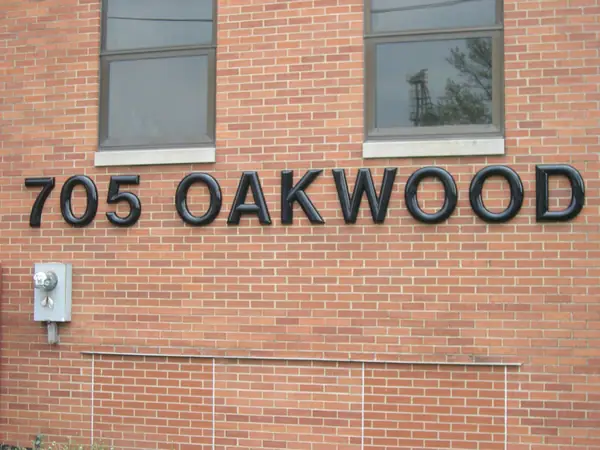 Individual cast letters and numerals mounted on a brick building wall, spelling a street address