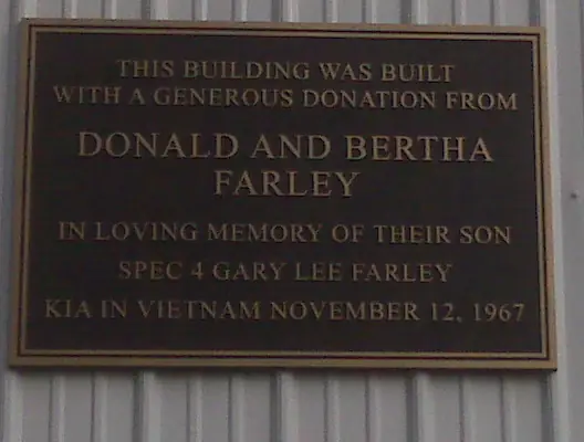 A cast bronze donor plaque with raised lettering, recording a building donation made in memory of a soldier killed in Vietnam