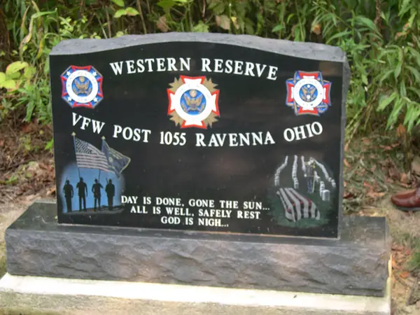 A polished black granite VFW post memorial for Ravenna, Ohio, etched with flags, a silhouetted colour guard, a folded flag and a verse