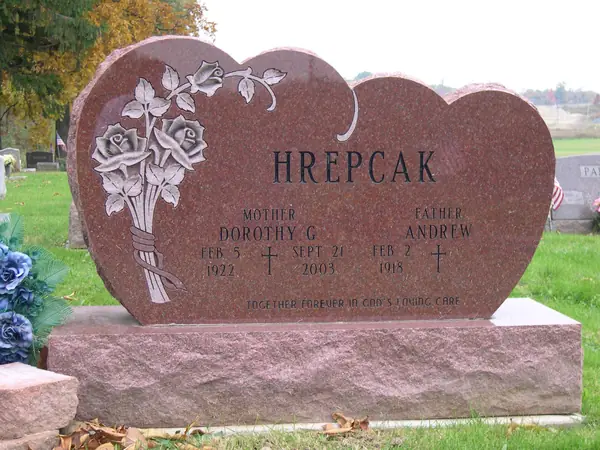 A red granite monument cut as three joined arches, with a carved bouquet of roses and two name tablets each headed by a relationship