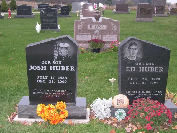 Two matching polished black granite monuments standing side by side in a family plot, each with an etched portrait, a relationship line and an epitaph