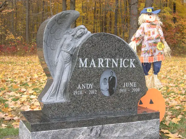 A monument pairing a carved figure of a mourning angel in light granite with a dark granite tablet carrying two names and a small oval portrait