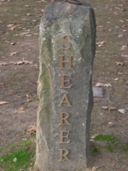A rough-cut natural granite pillar with the family name set vertically in gilt lettering