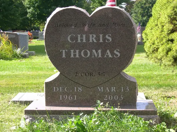 A rose granite monument cut as a heart on a stepped base, with a relationship line, the name in raised lettering and a scripture reference