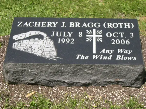 A polished dark granite bevel marker with an etched steam locomotive, a cross between the two dates and a short epitaph in script
