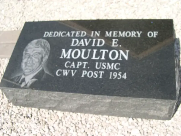 A polished black granite dedication marker with an etched portrait, a name, a service rank and a veterans post number
