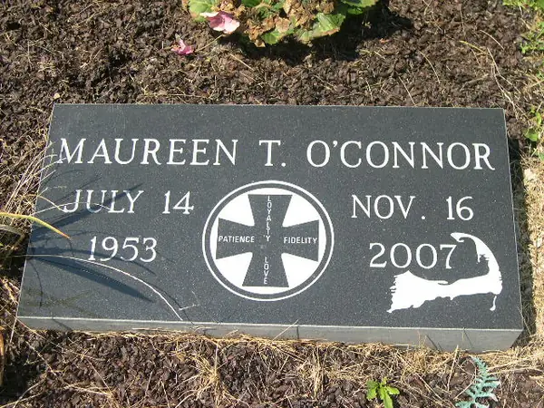 A polished black granite marker with a carved fraternal cross emblem between the dates and an etched coastline silhouette