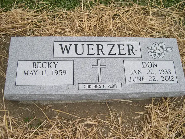 A grey granite marker with two name tablets either side of a carved cross, an anniversary emblem at one corner and a short epitaph
