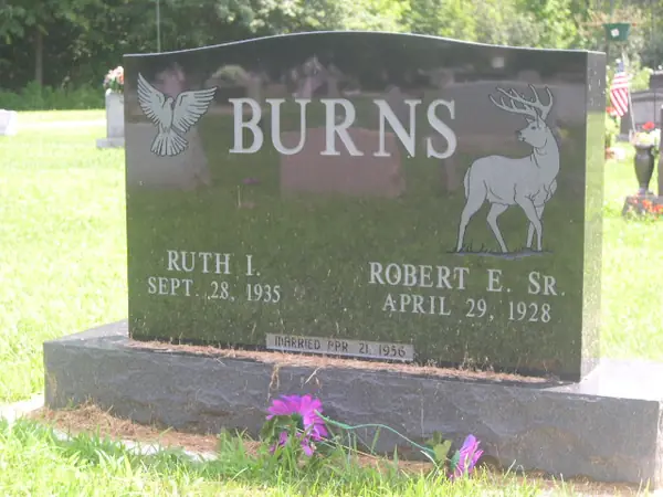 A dark grey polished granite upright monument with an etched dove at one shoulder and a standing buck at the other, and a marriage date cut into the base
