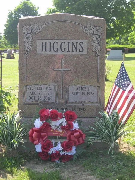 A rose granite upright monument with a raised name panel, roses carved at both upper corners and a cross between the two name tablets