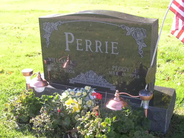A dark granite upright monument with roses carved at both upper corners, the family name in raised lettering and a marriage date banner between the two name tablets