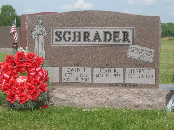 A rose granite upright monument with a carved figure of St Francis at one shoulder, a raised name panel and three name tablets labelled by relationship