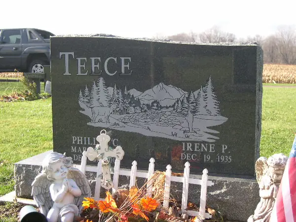 A polished dark grey granite upright monument with an etched woodland lake scene of deer and pines running the width of the face