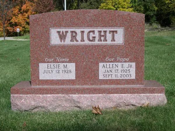 A red granite upright monument with a raised name panel and two name tablets, each headed by a term of endearment in script