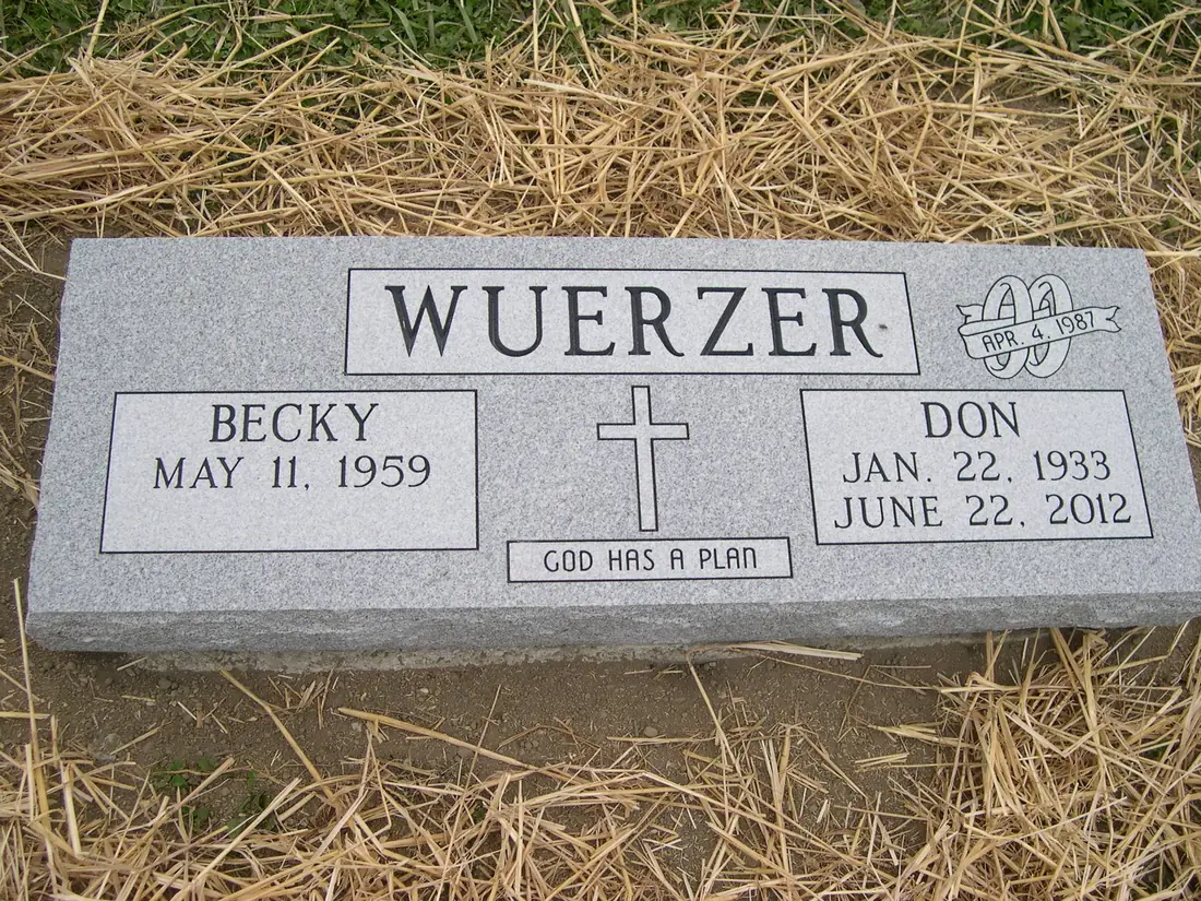 A flat granite marker with a surname across the top, a cross and a short line of scripture at the center, one name with a birth date only and the other with both dates.