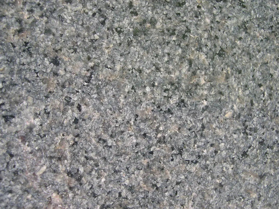 A close view of polished gray granite showing individual black, white and gray mineral flecks.