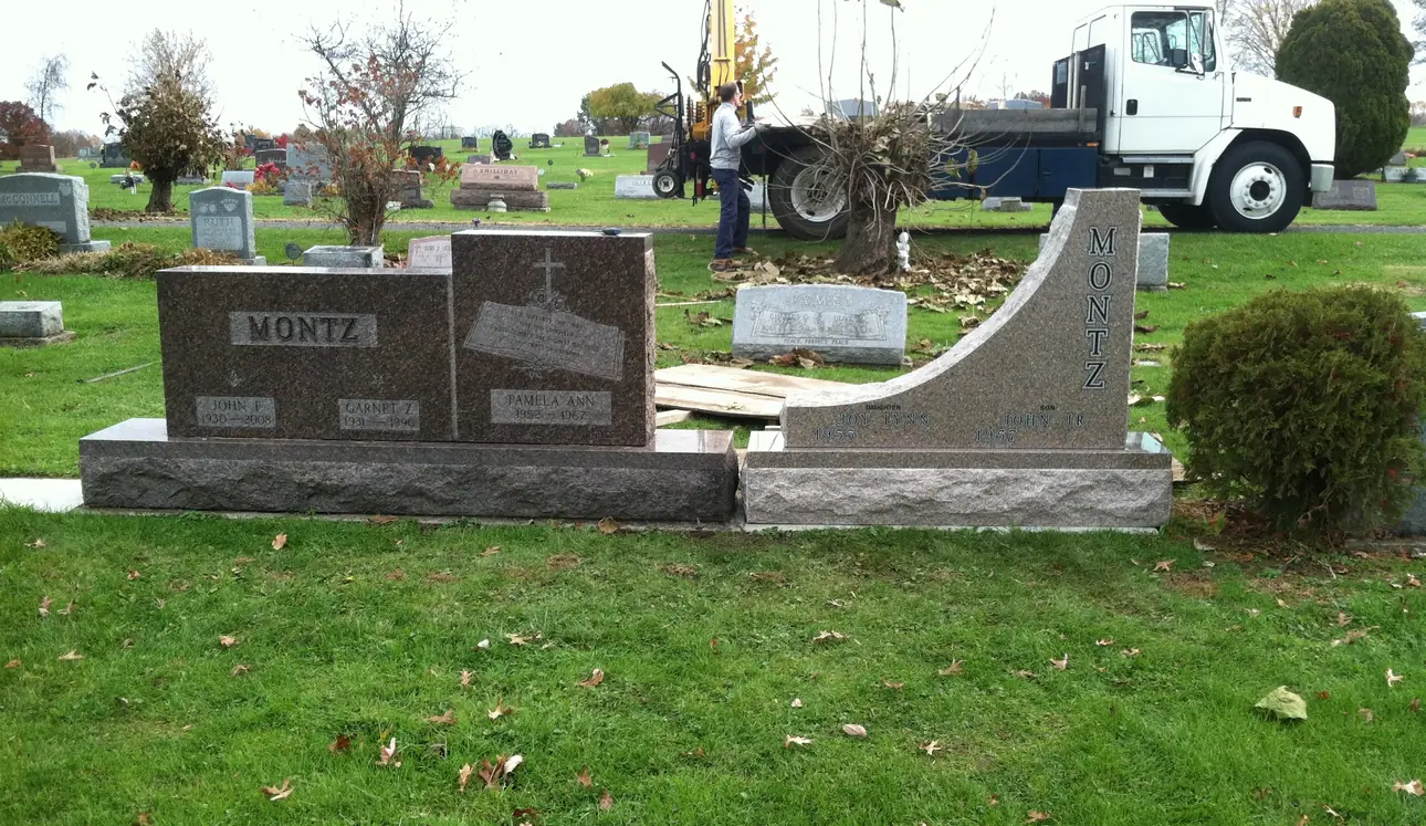 A monument and matching granite bench being set at an Ohio cemetery, with the boom truck still alongside the grave.
